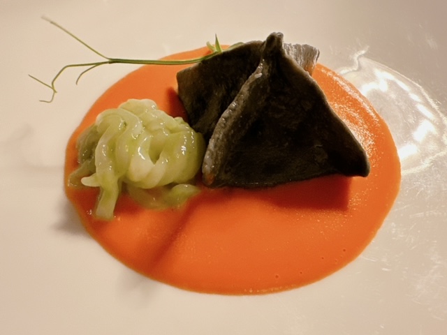Raviolo al nero con merluzzo mantecato, vellutata di pomodoro e julienne di calamari marinati al basilico 